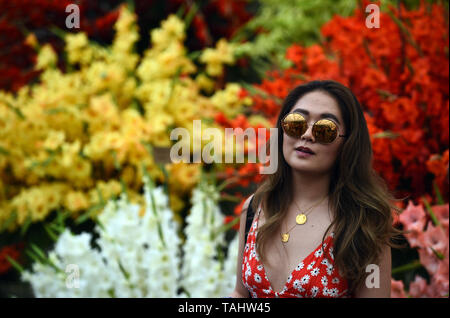 Un visiteur se pose pour une photo en face de fleurs au RHS Chelsea Flower Show au Royal Hospital Chelsea, Londres. Banque D'Images