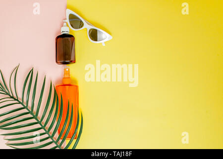 Sunblock sur bouteille carrée jaune lumineux et fond rose. Le concept de la station en mer, l'heure d'été. Haut de la vue, télévision lay, minimalisme, copy space Banque D'Images