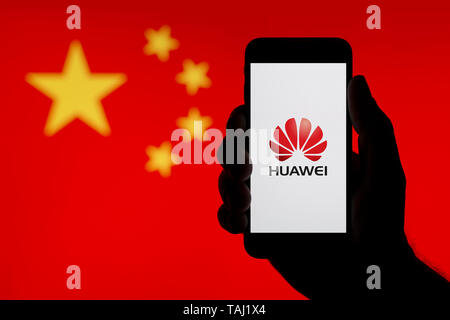 La silhouette d'une main d'un homme est titulaire d'un smartphone affichant le logo de l'entreprise chinoise Huawei, avec un drapeau de la Chine dans l'arrière-plan (usage éditorial uniquement) Banque D'Images