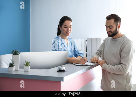 Jeune homme près de réception en clinique Banque D'Images