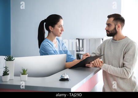 Jeune homme près de réception en clinique Banque D'Images