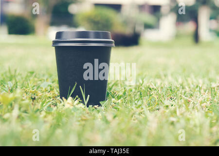 Le papier noir de tasses de café pour aller sur l'herbe. Place pour votre texte ou logo sur CUPS. Banque D'Images