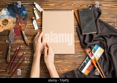 Mains de l'artiste féminine, des outils et des peintures sur fond de bois, vue du dessus Banque D'Images