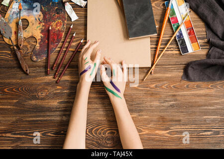 Mains de l'artiste féminine, des outils et des peintures sur fond de bois, vue du dessus Banque D'Images