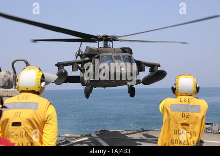 190522-A-BM388-04 un marin de la Marine américaine l'armée américaine guides un UH-60 Black Hawk affecté à la Compagnie Bravo, 2e Bataillon, 147e Régiment d'aviation, 8e bataillon du 229e Régiment d'aviation au cours de qualifications d'appontage à bord de la classe Arleigh Burke destroyer lance-missiles USS Gonzalez (DDG 66), le 22 mai 2019 dans la région du Golfe. La Gonzalez déployés à l'U.S. Central Command zone d'opérations pour renforcer la sécurité et la stabilité de la région. Qualifications d'appontage d'accroître l'interopérabilité entre l'armée américaine et de la Marine. (U.S. Photo de l'armée par le sergent. Justin Hardin Banque D'Images