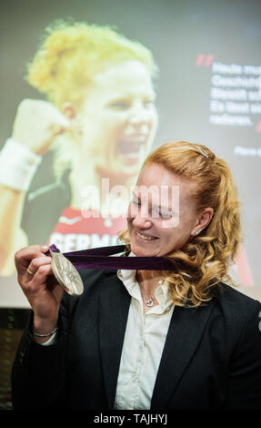 L'ancien lanceur de marteau Donald Béchard Betty est avec une médaille d'argent en face d'une photo, ce qu'elle montre aux Jeux Olympiques 2012 à Londres. L'athlète a été par la suite reçu la médaille d'argent parce que le russe alors gagnant a été disqualifié pour dopage aux Jeux Olympiques de 2012 à Londres. Photo : Andreas Arnold/dpa Banque D'Images