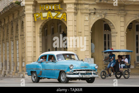 La Havane, Cuba - un taxi et un vélo taxi passent devant l'hôtel Plaza près de Parque Central. Classic voitures américaines des années 50, importées avant l'U Banque D'Images