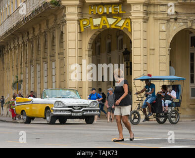 La Havane, Cuba - un taxi et un vélo taxi passent devant l'hôtel Plaza près de Parque Central. Classic voitures américaines des années 50, importées avant l'U Banque D'Images