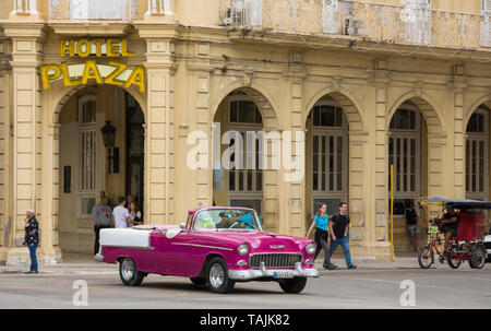 La Havane, Cuba - un taxi et un vélo taxi passent devant l'hôtel Plaza près de Parque Central. Classic voitures américaines des années 50, importées avant l'U Banque D'Images