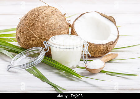 L'huile de noix de coco dans un bocal en verre hermétique et cuillère en bois blanc sur les plaques tableau Banque D'Images