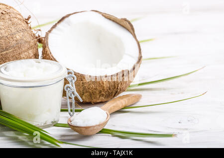 L'huile de noix de coco dans un bocal en verre hermétique et cuillère en bois blanc sur les plaques tableau Banque D'Images