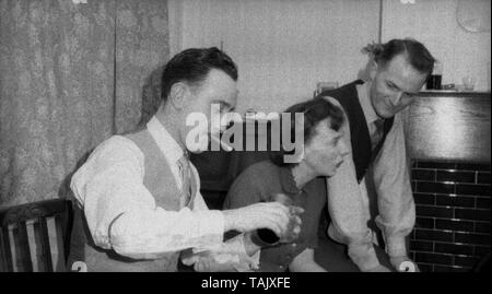 Années 1950, historique, rencontre sociale, deux hommes et une femme assise dans une chambre à l'avant, l'un des hommes fumeurs un min-cigare et lui-même verser un verre, England, UK. Banque D'Images