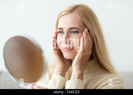 À la recherche de miroir. Woman Touching her Face Banque D'Images
