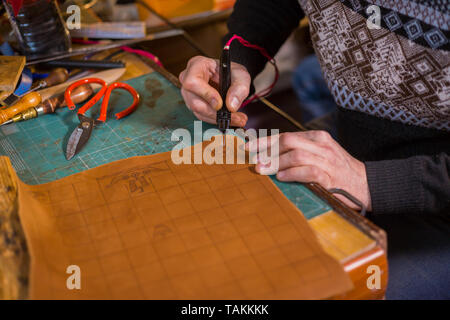 Professionnel hommes skinner, tanner faire détails décoratifs sur le cuir du jeu pour jeu de stratégie avec pyrographic -tafl spécial machine Banque D'Images