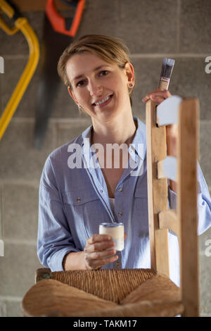 Portrait de femme mature à l'atelier de meubles Upcycling Accueil Peinture chaise en bois Banque D'Images