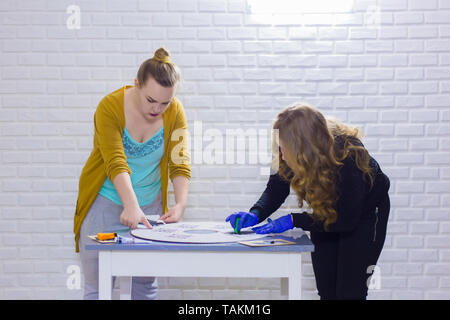 Deux femmes designers, décorateurs professionnels en bois peinture au pochoir décoration cercle à l'atelier, studio. La peinture, l'art artisanal et concept Banque D'Images