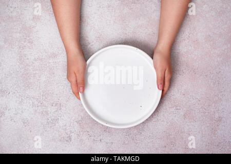 Les mains tiennent un vide plaque en céramique (bac). Vue de dessus. copy space Banque D'Images
