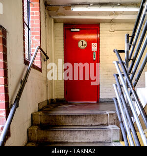 Rouge d'urgence interne porte coupe-feu en haut d'un escalier en béton Banque D'Images