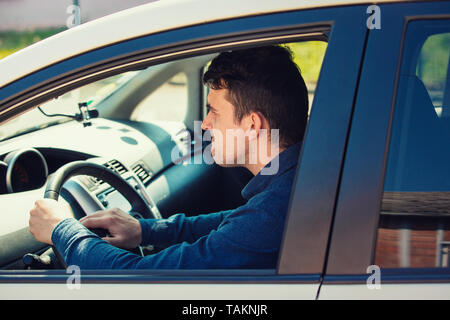 Portrait de furious conducteur assis dans la voiture et le klaxon de voiture klaxonnant fâché sur le pilote de l'avant. Guy agressif en attente dans les embouteillages, bip Banque D'Images