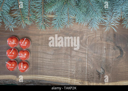 Bougies rouges en forme de cœur et branches sur un fond boisé Banque D'Images