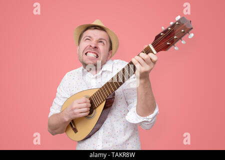 L'homme en été hat jouent de la guitare et chanter des chansons. Banque D'Images