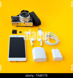 Pour l'appareil photo d'un photographe, d'un casque sans fil accessoires et le chargeur et le smartphone pour toutes les applications et des abonnements, fond jaune Banque D'Images