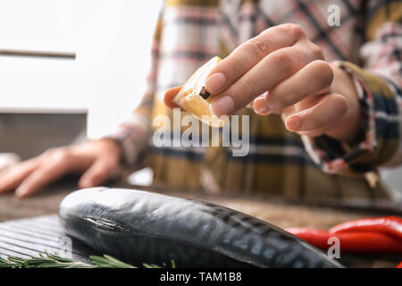 Woman squeezing jus de citron sur le maquereau, poisson savoureux closeup Banque D'Images