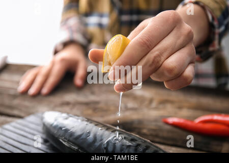 Woman squeezing jus de citron sur le maquereau, poisson savoureux closeup Banque D'Images