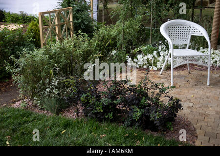 Chaise blanche en plastique dans le jardin pour se détendre Banque D'Images