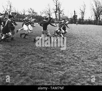 Années 1960, historiques, match de rugby amateur, deux mâles adultes rugby les joueurs se font concurrence pour le ballon au sol, tandis que leurs coéquipiers, à l'appui, England, UK. Banque D'Images