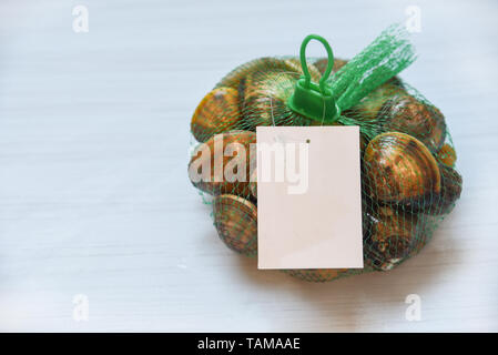 L'émail des mollusques bivalves de fruits de mer coquille de Vénus sur sac net dans le supermarché Banque D'Images