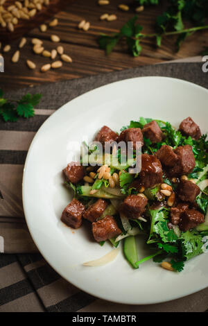 Boeuf braisé avec du persil, concombre, noix de pin et oignons doux. Cafe menu sur un fond de bois dans des couleurs chaudes avec copie espace. Banque D'Images