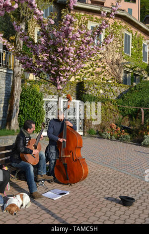 Varenna/Italie - 6 Avril 2014 : deux musiciens jouant de la guitare classique et contrebasse au lac Varenna dans une journée de printemps ensoleillée. Banque D'Images