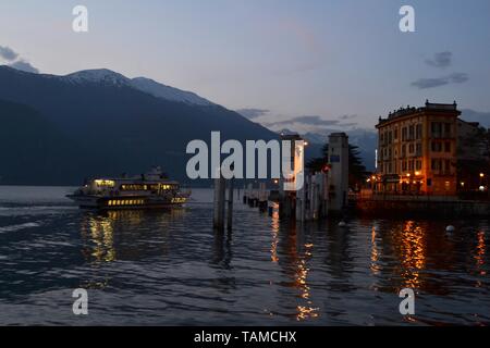 Varenna/Italie- 6 avril 2014 : Belle vue panoramique sur le lac de Côme avec navire à passagers arrivant au port de Varenna au coucher du soleil au printemps. Banque D'Images