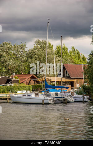 Voiliers se situent sur une jetée avec une belle maison en bois dans l'arrière-plan Banque D'Images