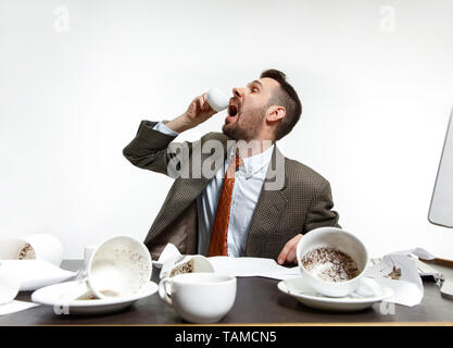 N'a pas de temps pour se reposer. Jeune homme de boire beaucoup de café, mais ne peut pas se réveiller et de travailler de toute façon. Continuer à dormir au bureau. Concept d'office worker' Banque D'Images