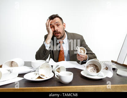 N'a pas de temps pour se reposer. Jeune homme de boire beaucoup de café, mais ne peut pas se réveiller et de travailler de toute façon. Continuer à dormir au bureau. Concept d'office worker' Banque D'Images