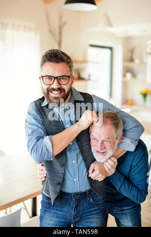 Un adulte hipster fils et père des cadres supérieurs à l'intérieur à la maison, avoir du plaisir. Banque D'Images