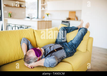 Man masque yeux allongé sur un canapé à l'intérieur à la maison, se détendre. Banque D'Images