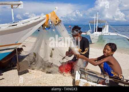 Pêcheur prend la capture dans la filet de pêche, Bounty beach, Malapascua Island, Cebu, Philippines Banque D'Images