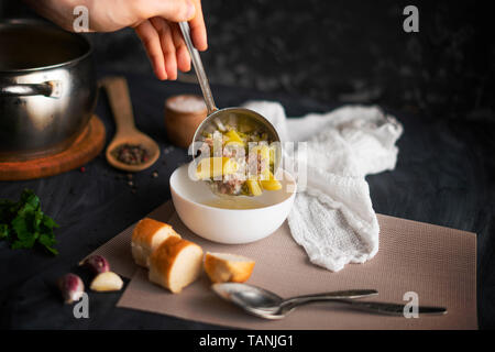 Par ailleurs chefs verser de la soupe dans un bol vide blanc, la préparation des aliments Banque D'Images