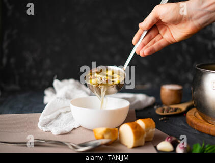 Par ailleurs chefs verser de la soupe dans un bol vide blanc, la préparation des aliments Banque D'Images