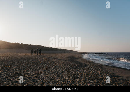 Horsey Gap, France - le 19 avril 2019 : Les gens qui marchent sur la plage par l'écart Horsey mer au coucher du soleil. Horsey beach est célèbre pour l'observation de phoques dans la région de Norf Banque D'Images