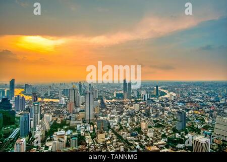 Vue panoramique aérienne de beau coucher du soleil orange ciel au-dessus des toits du centre-ville d'affaires central de la ville de Bangkok avec vue courbe de Chao Phraya. Banque D'Images