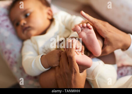 Close-up d'une mère noire holding pieds de bébé dans les mains et profiter du temps ensemble, de maternité concept Banque D'Images