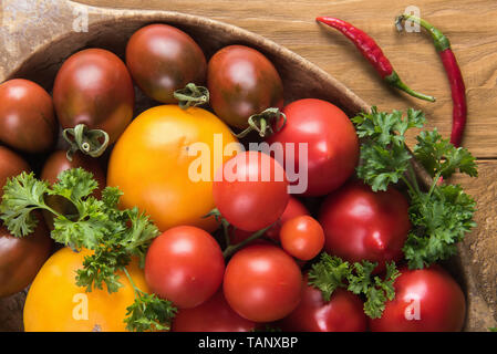 Close up de tomates biologiques différents frais, avec le persil et le poivron vert. Surface de la table en bois naturel. Focus sélectif. La saine alimentation et de di Banque D'Images