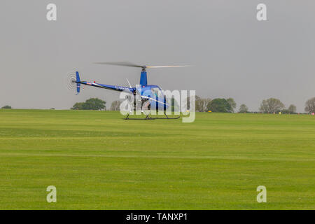 Un hélicoptère Robinson R-22 Beta voler contre un ciel sombre au cours de l'après-midi à Sywell Northamptonshire, l'aérodrome Banque D'Images