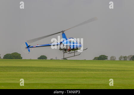 Un hélicoptère Robinson R-22 Beta voler contre un ciel sombre au cours de l'après-midi à Sywell Northamptonshire, l'aérodrome Banque D'Images