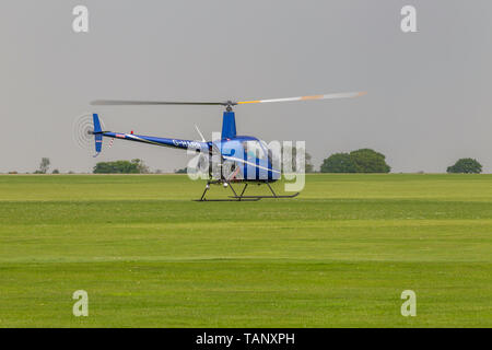 Un hélicoptère Robinson R-22 Beta voler contre un ciel sombre au cours de l'après-midi à Sywell Northamptonshire, l'aérodrome Banque D'Images