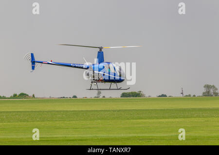 Un hélicoptère Robinson R-22 Beta voler contre un ciel sombre au cours de l'après-midi à Sywell Northamptonshire, l'aérodrome Banque D'Images